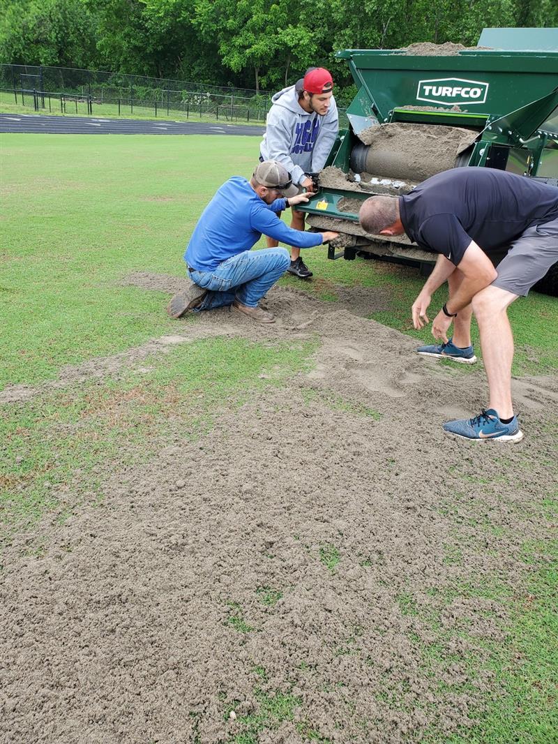 Nate Horn with  John Deere sales rep, Justin Ross, calibrating and unclogging the topdresser